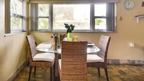 Un coin repas avec des chaises en osier, une table en verre et un ventilateur de plafond.
