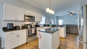 A modern kitchen with white cabinets, a central island, stainless steel appliances, and a ceiling fan. - Disney-area Home w/ Private Pool in Davenport! (Davenport)