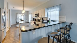 A modern kitchen with a central island, bar stools, stainless steel appliances, and a pendant light. - Disney-area Home w/ Private Pool in Davenport! (Davenport)