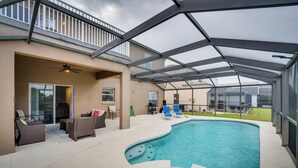 A covered outdoor swimming pool with lounge chairs and a patio area. - Disney-area Home w/ Private Pool in Davenport! (Davenport)