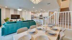 Une cuisine moderne avec des meubles blancs, un îlot central et un coin repas avec une table dressée pour six personnes.