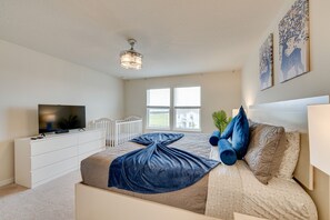 Une chambre à coucher avec un lit, une télévision, un berceau et une fenêtre avec des stores.