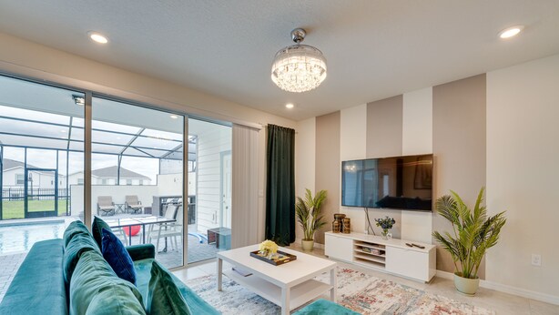 Un salon moderne avec un canapé vert, une table basse blanche et un téléviseur à écran plat.