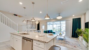 Une cuisine moderne dotée de plans de travail en granit, d’appareils électroménagers en acier inoxydable et de luminaires suspendus.