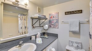 A bathroom with a sink, mirror, towel rack, and a sign that says "Welcome To The Beach". - New Smyrna Beach Condo w/ Pool & Beach Access! (New Smyrna Beach)