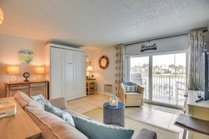 Een woonkamer met een bank, een salontafel en uitzicht op de omgeving door een schuifdeur.