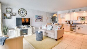 A modern living room with a sofa, TV, and decorative items. - New Smyrna Beach Condo w/ Pool & Beach Access! (New Smyrna Beach)