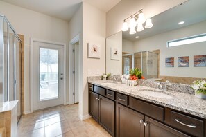 A modern bathroom with a large mirror, granite countertop, and dark cabinetry. - Magical Disney Getaway w/ Pool & Game Room! (Kissimmee)