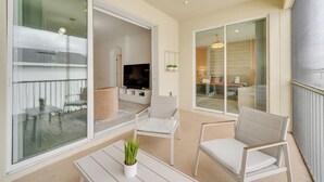 Ein Balkon mit weißen Stühlen, einem kleinen Tisch und einem Blumentopf.