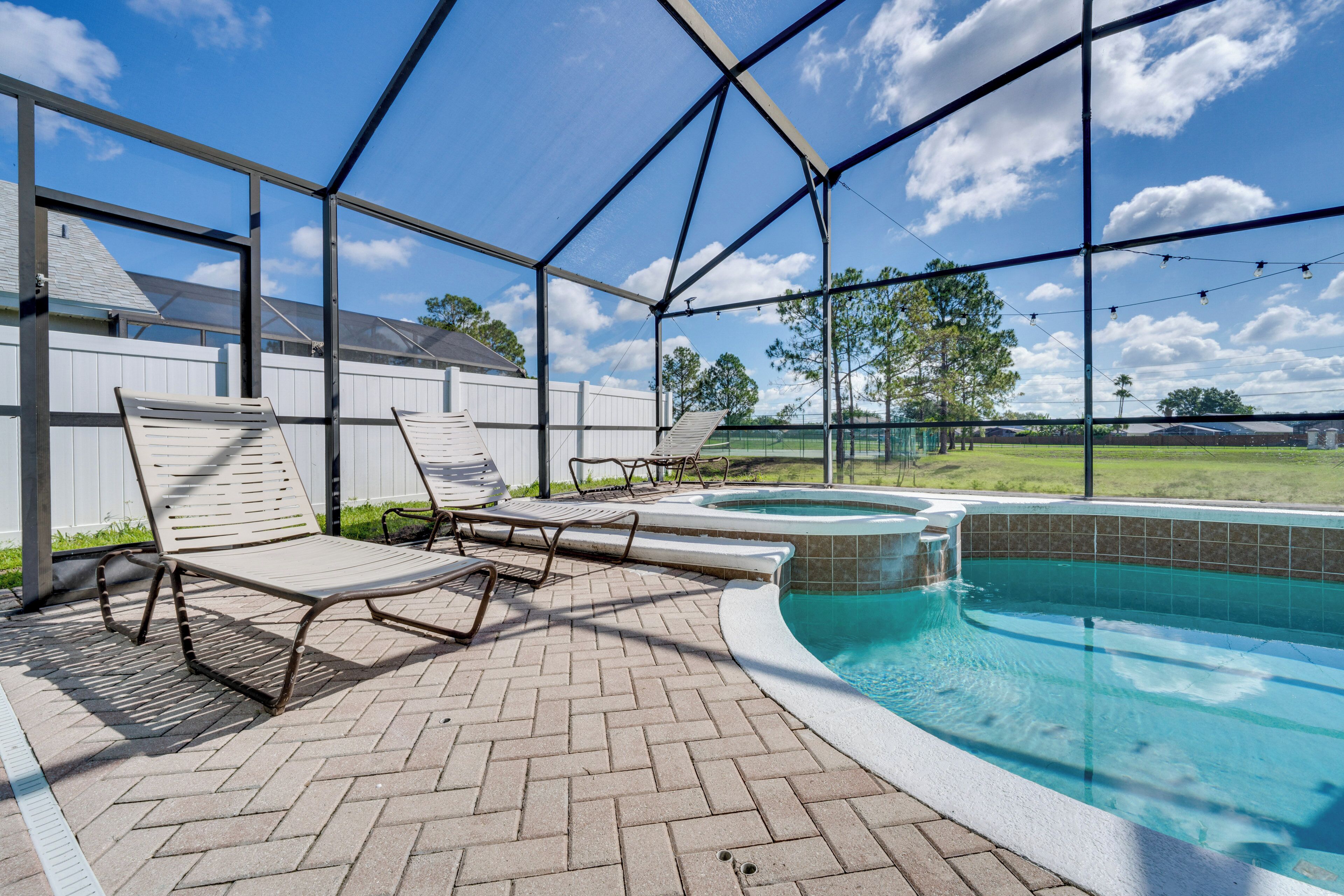 An outdoor swimming pool area with lounge chairs and a hot tub.