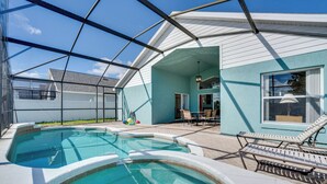 A swimming pool with a glass enclosure, lounge chairs, and a patio area with outdoor furniture. - 4 Mi to Disney: Family Getaway w/ Game Room! (Kissimmee)