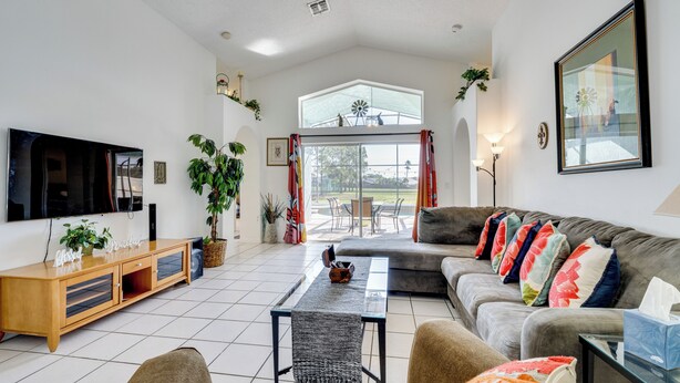 A living room with a sofa, TV, and a dining area with a table and chairs. - 4 Mi to Disney: Family Getaway w/ Game Room! (Kissimmee)