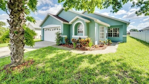 A single-story house with a garage, a well-maintained lawn, and a palm tree in the foreground. - 4 Mi to Disney: Family Getaway w/ Game Room! (Kissimmee)