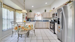A kitchen with a dining table, chairs, a refrigerator, and cabinets. - 4 Mi to Disney: Family Getaway w/ Game Room! (Kissimmee)