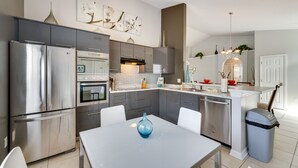 A modern kitchen with stainless steel appliances, a grey countertop, and a blue vase on the table. - Davenport Vacation Rental w/ Private Pool! (Davenport)