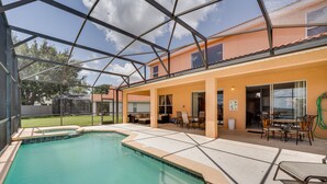 Une piscine dotée d’une enceinte en verre, d’un espace extérieur aménagé pour s’asseoir et d’un patio couvert.