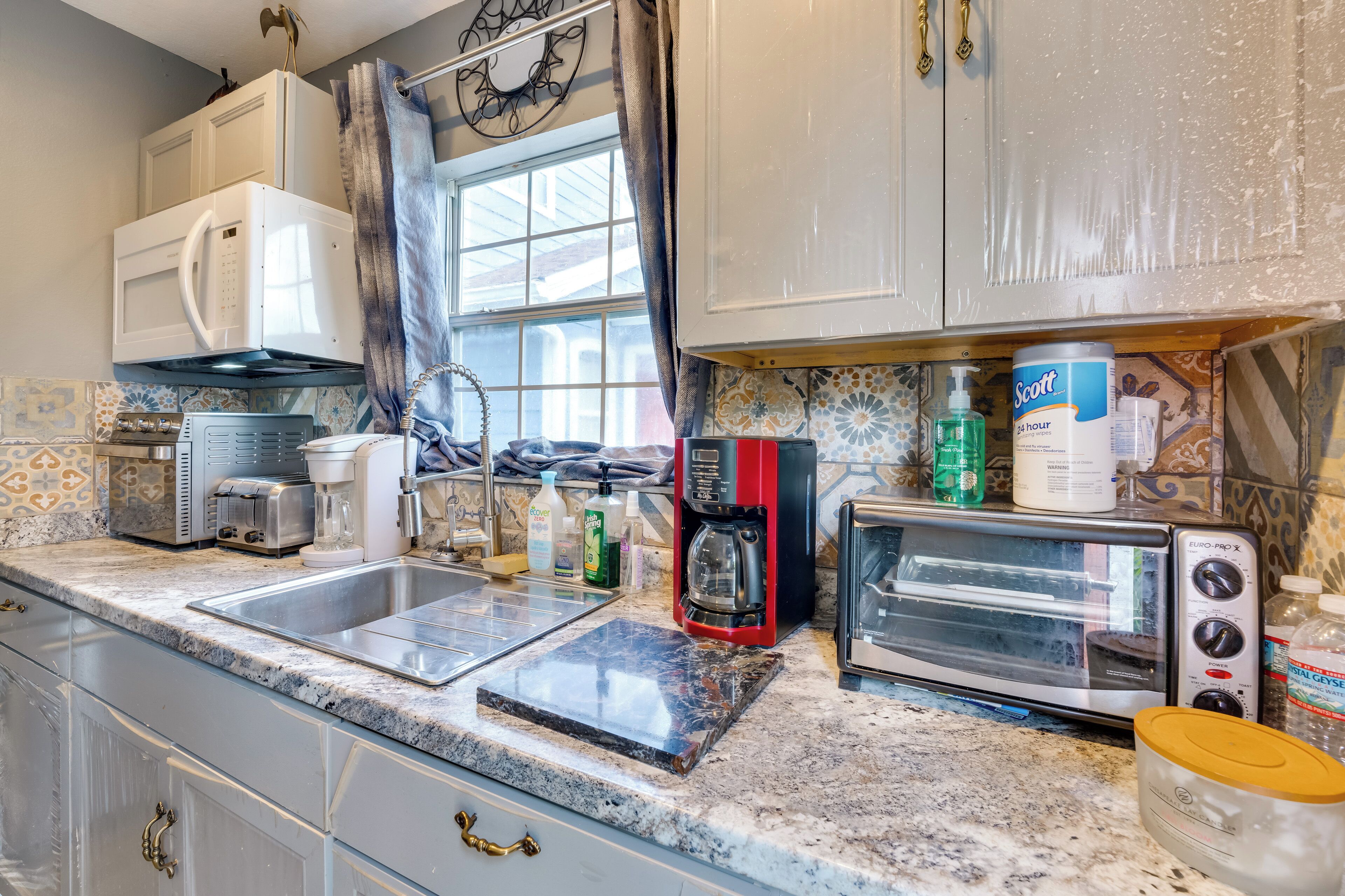 A kitchen with a double sink, a coffee maker, a toaster, and a microwave.