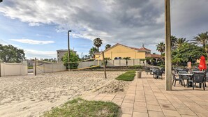 Une zone de plage sablonneuse avec un filet de volley-ball, une promenade dallée et des espaces de repos en plein air.
