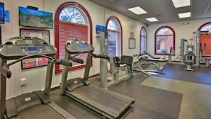 Une salle de sport équipée de tapis de course, d’appareils de musculation et de tapis d’exercice.