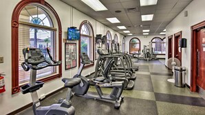 A gym with multiple treadmills and exercise equipment, large windows with blinds, and a checkered floor. - 9 Mi to Disney: Regal Palms Townhome w/ Patio! (Davenport)