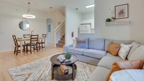 A modern living room with a sofa, coffee table, and dining area. - 9 Mi to Disney: Regal Palms Townhome w/ Patio! (Davenport)
