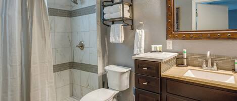Un baño con ducha, inodoro, lavamanos y tocador.