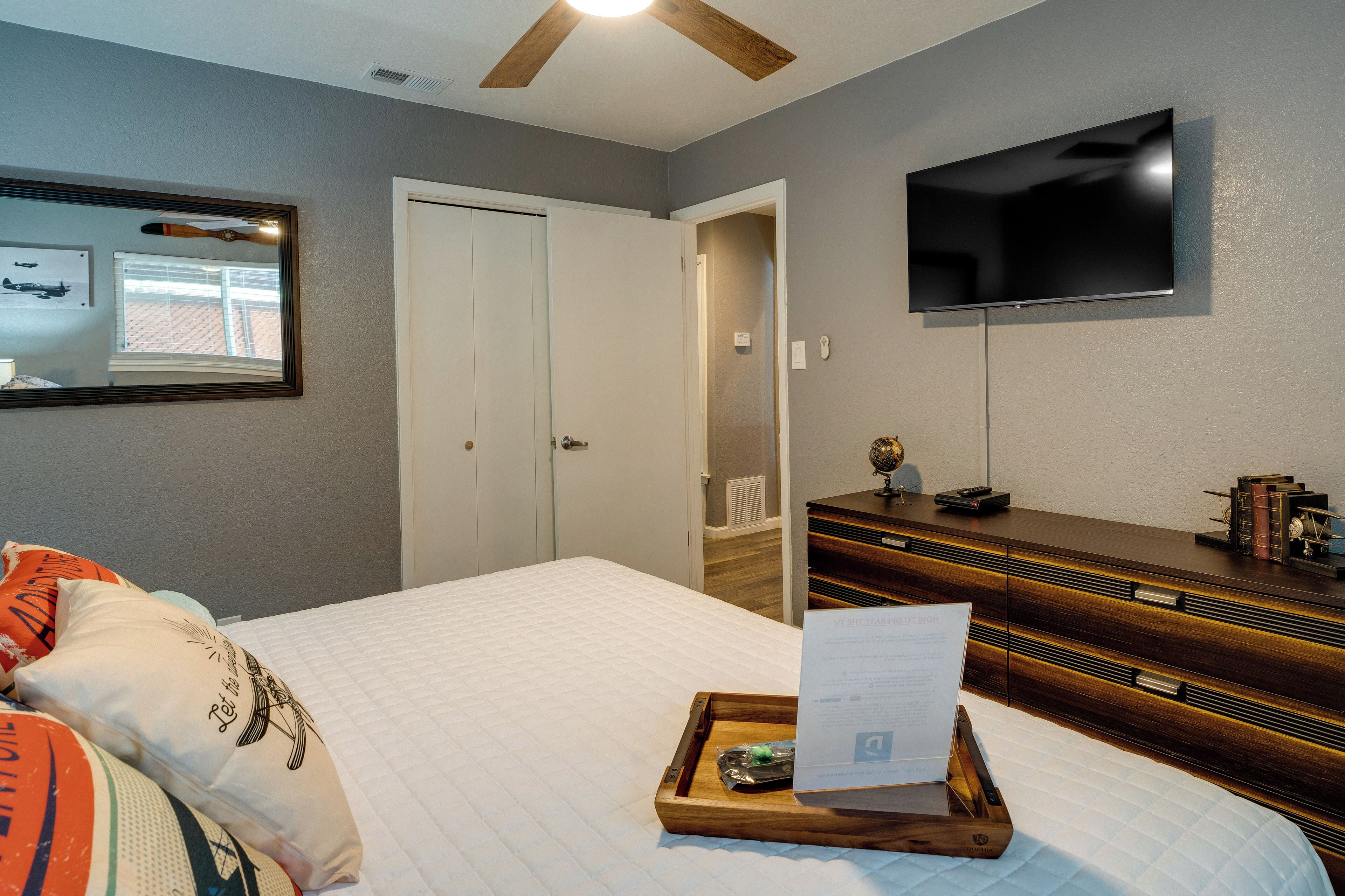 Une chambre à coucher avec un lit, une commode, un téléviseur et un miroir.