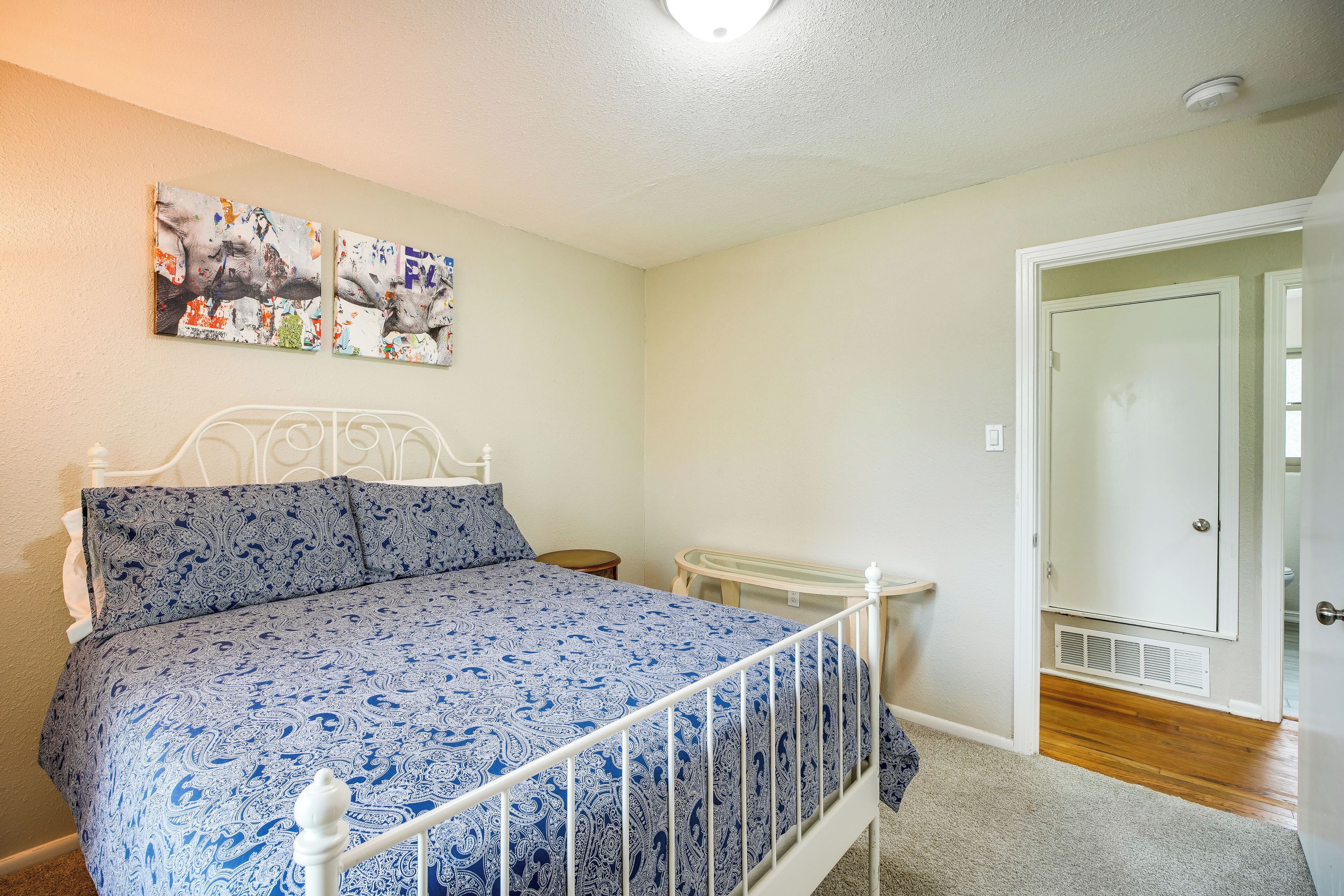 Een slaapkamer met een bed, een tafeltje en een deur naar een andere kamer.
