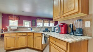 A modern kitchen with wooden cabinets, a granite countertop, and various appliances including a blender and coffee maker.