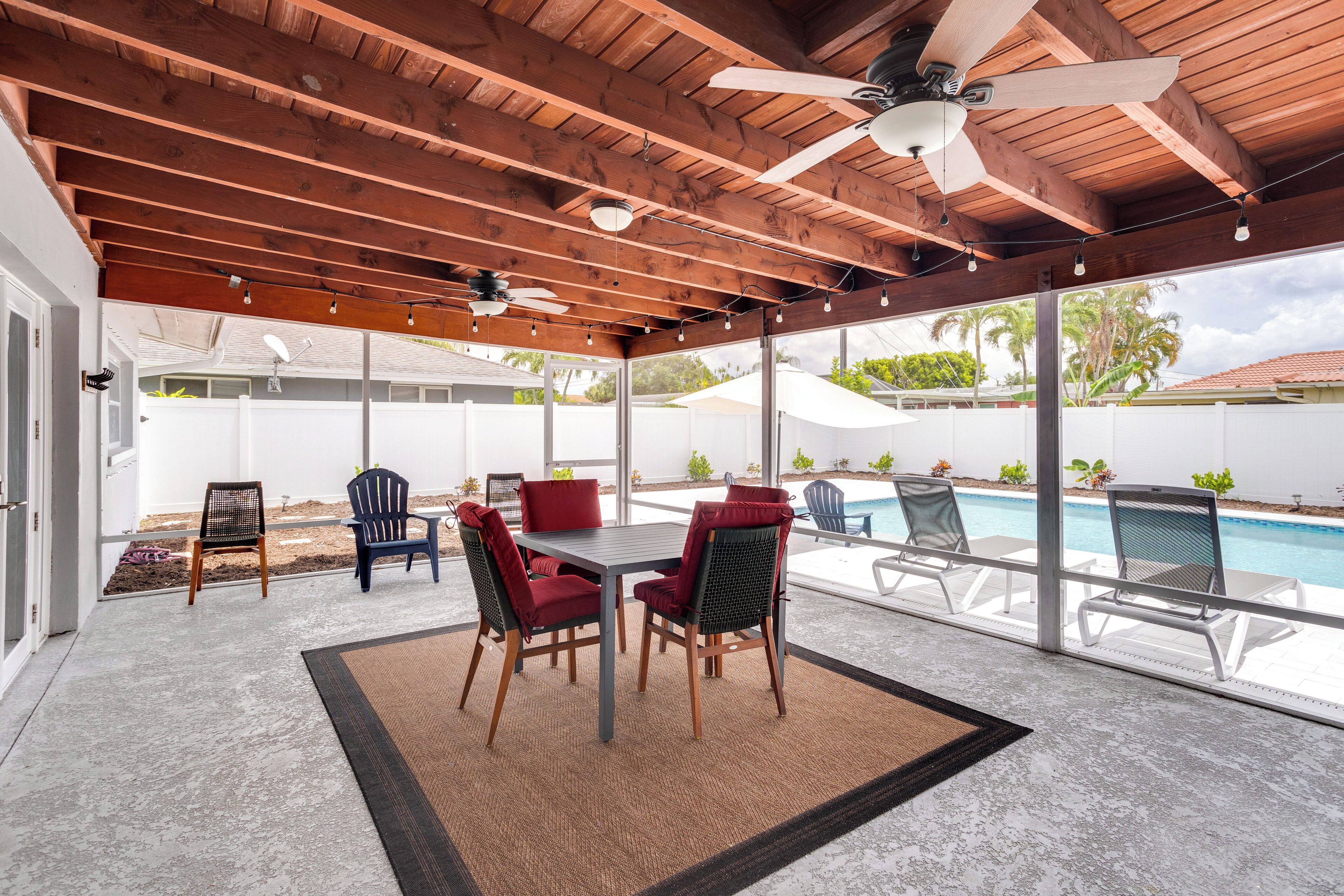 An outdoor patio with a pool, wooden ceiling beams, and a table with chairs.