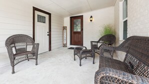 A covered porch with wicker furniture, a welcome sign, and a door with a window. - Spacious San Antonio Retreat w/ Private Patio! (San Antonio)