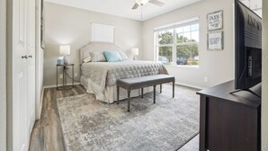 A bedroom with a bed, bedside tables, a bench, a ceiling fan, a window, and a TV. - Spacious San Antonio Retreat w/ Private Patio! (San Antonio)