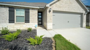 A two-story house with a stone facade, a garage, and a landscaped front yard with shrubs. - San Antonio Getaway w/ Private Yard & Smart TV (San Antonio)