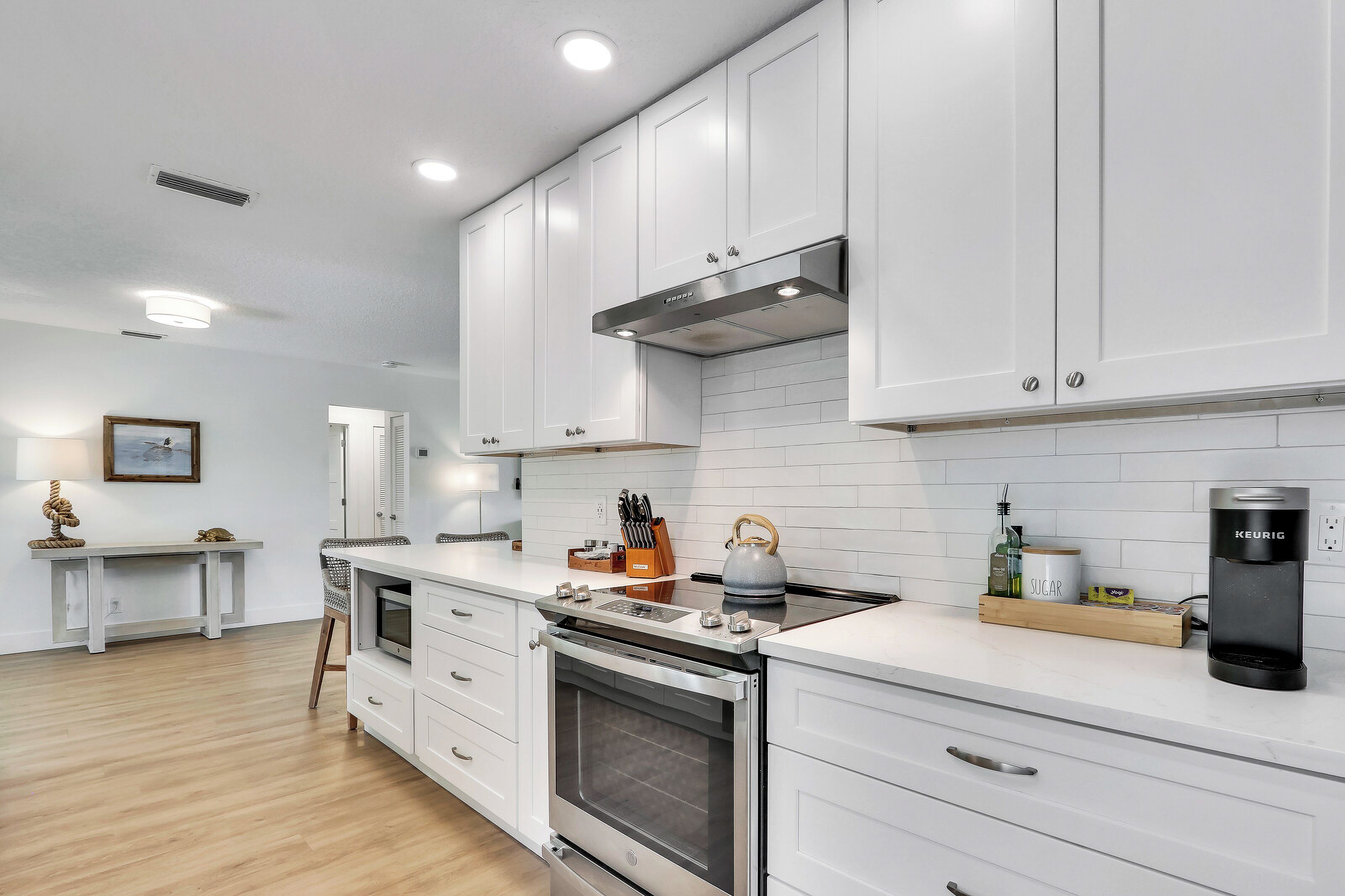 A modern kitchen with white cabinets, a stainless steel range hood, and a built-in oven.