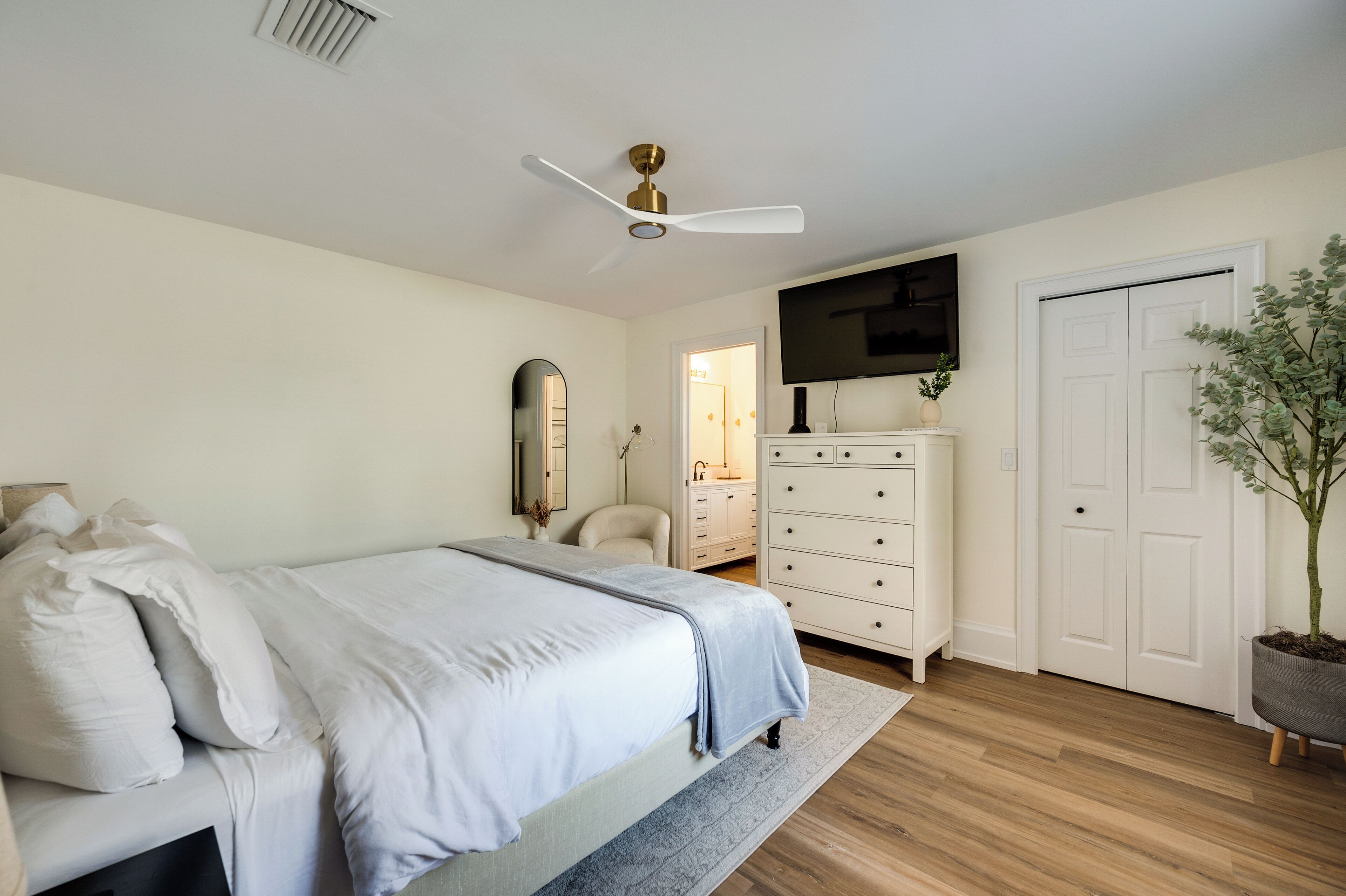 Un dormitorio con cama, cómoda, televisor y una puerta.