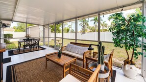 Un patio couvert avec un banc, une table et des chaises en bois.