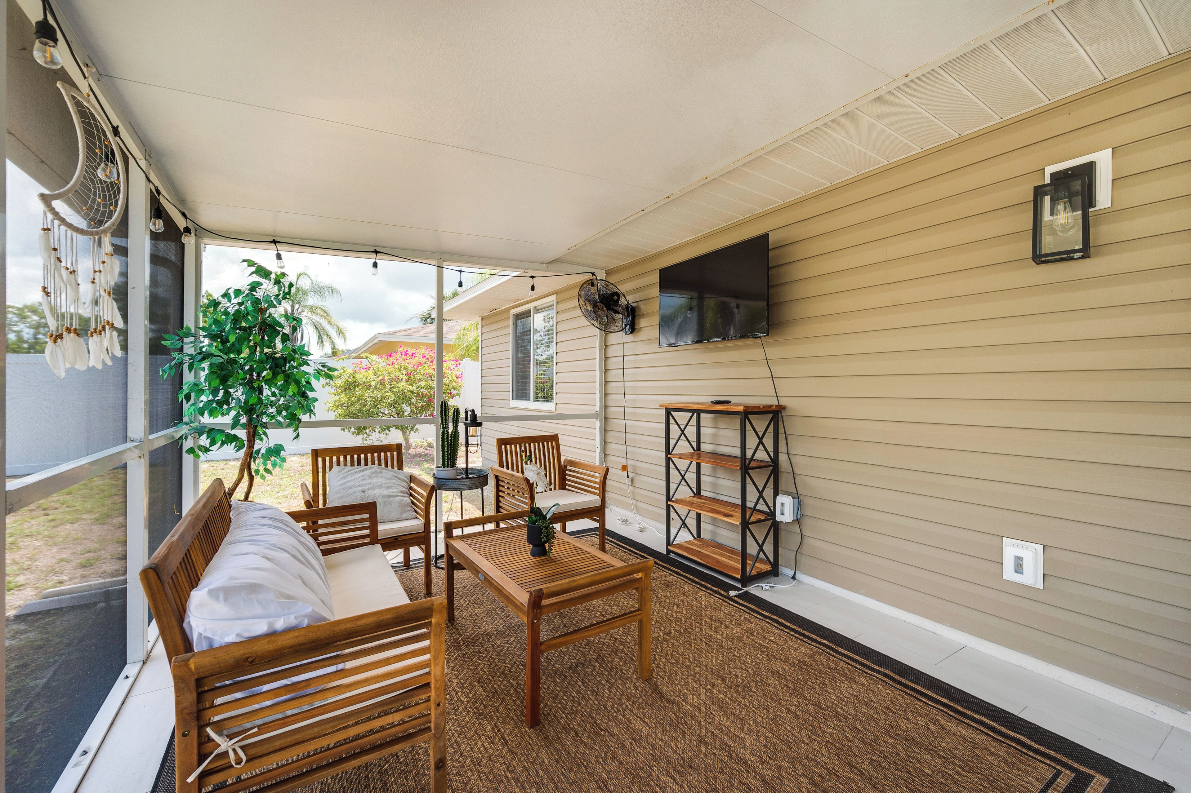 A covered patio with wooden furniture, a fan, and a TV mounted on the wall.