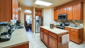 A kitchen with wooden cabinets, a stainless steel refrigerator, a microwave, and a toaster. - North San Antonio Vacation Rental w/ Yard & Deck! (San Antonio)
