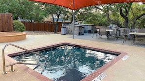 A hot tub with a 'No Diving' sign, surrounded by a deck with outdoor furniture and a stone wall. - North San Antonio Vacation Rental w/ Yard & Deck! (San Antonio)