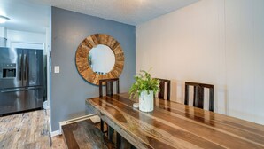 A modern dining area with a wooden table, chairs, a large mirror, and a potted plant. - Anchorage Home ~ 7 Mi to Chugach State Park! (Anchorage)