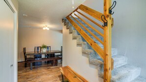 A wooden staircase with a handrail and a dining area with a table and benches. - Anchorage Home ~ 7 Mi to Chugach State Park! (Anchorage)