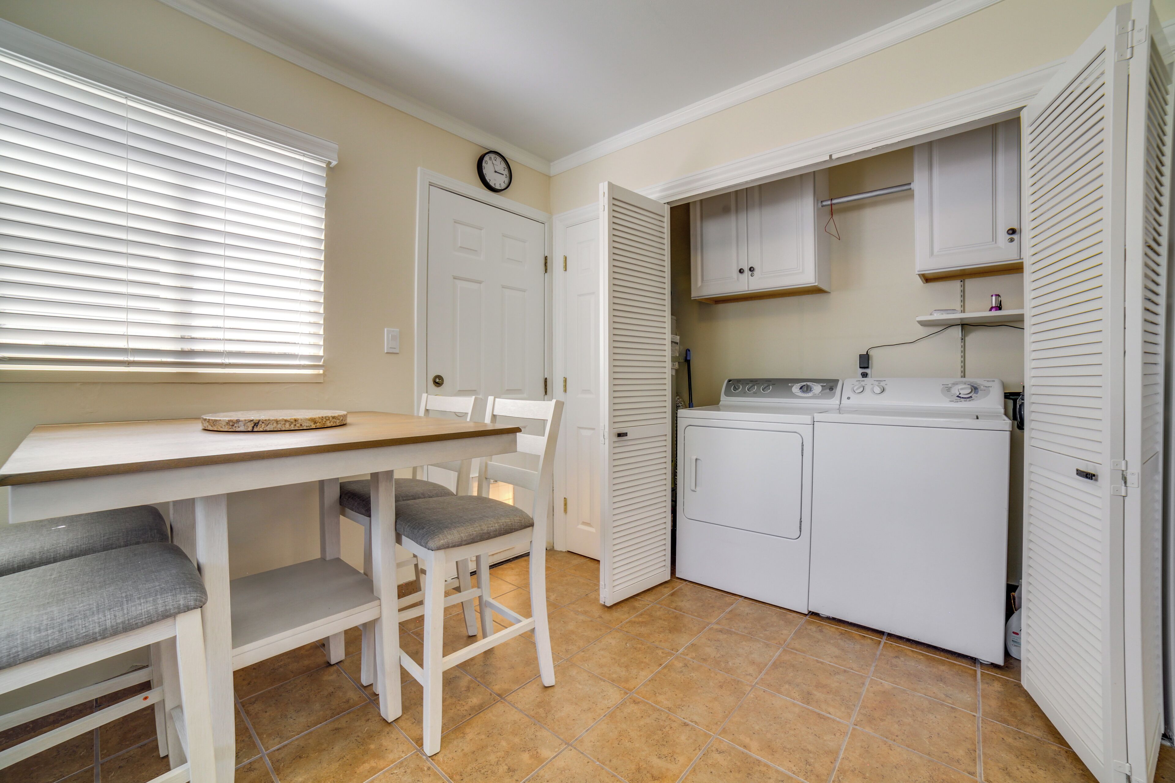 A compact laundry room with a washing machine, a dryer, and a table with chairs.