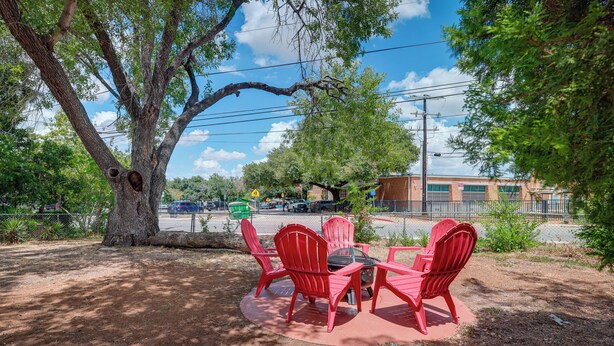 A picnic table with red chairs in a shaded area with trees.