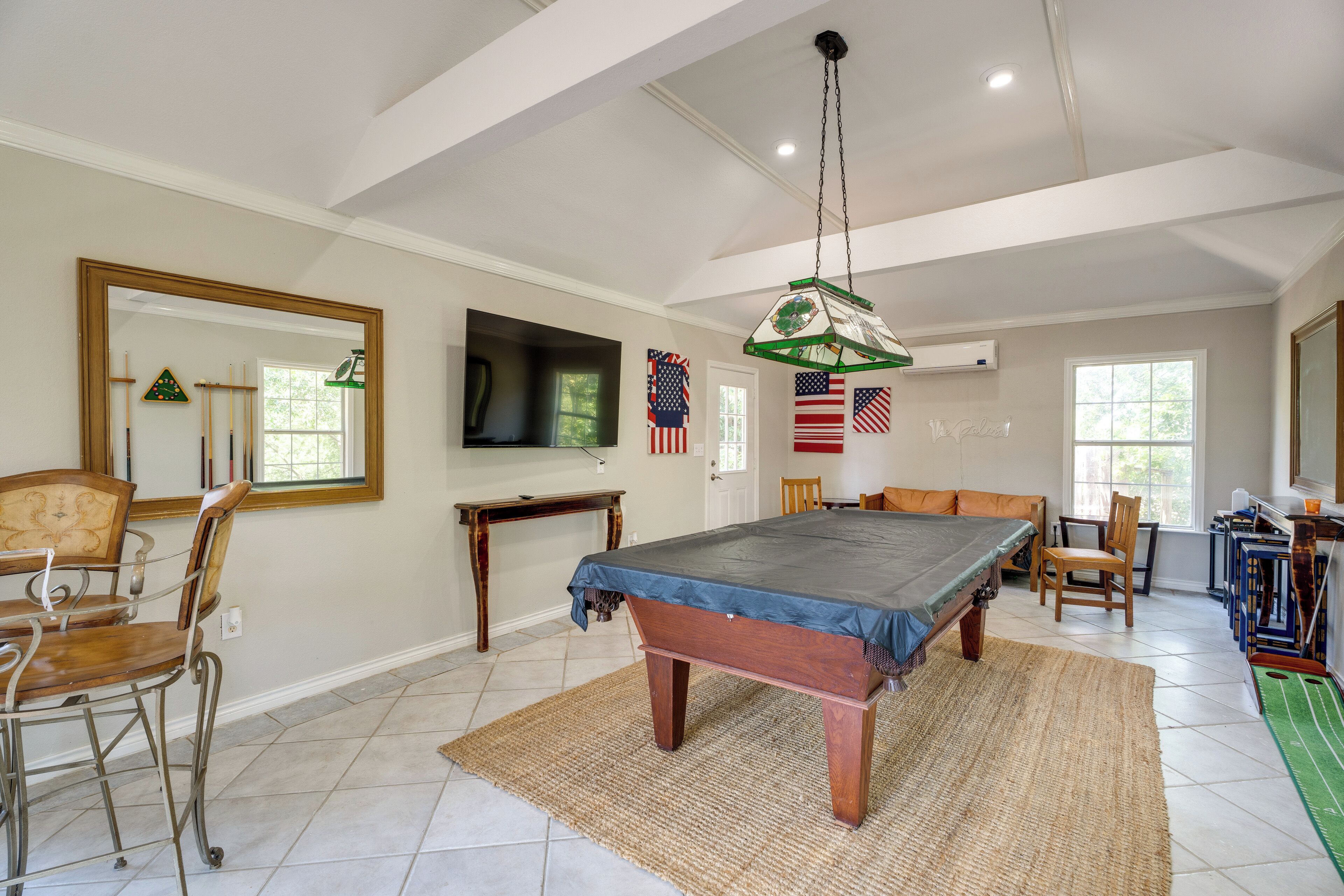 A spacious room with a pool table, chairs, and a television.