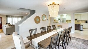 Une salle à manger spacieuse avec une longue table en bois, de nombreuses chaises et un lustre.