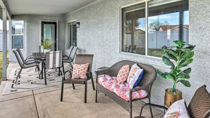 A covered patio with wicker furniture, a potted plant, and a large window.