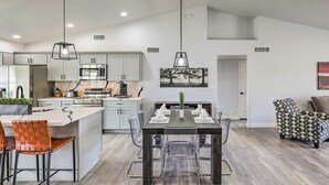 A modern kitchen with grey cabinets, a central island, and a dining area with a table and chairs.