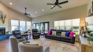 A spacious living room with a fireplace, leather sofas, and a ceiling fan. - 1 Mi to Water Ranch! Family Retreat w/ Resort Pool (Gilbert)