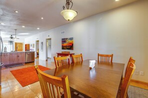 A spacious dining area with a wooden table and chairs, a ceiling fan, and a painting on the wall.