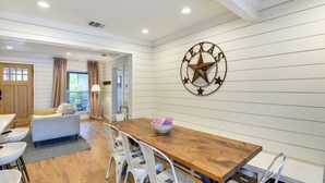 A dining area with a wooden table, white chairs, and a Texas state star wall decoration. - Pecan Blue Frisco Hub: Dtwn, Dining & Stadiums! (Frisco)